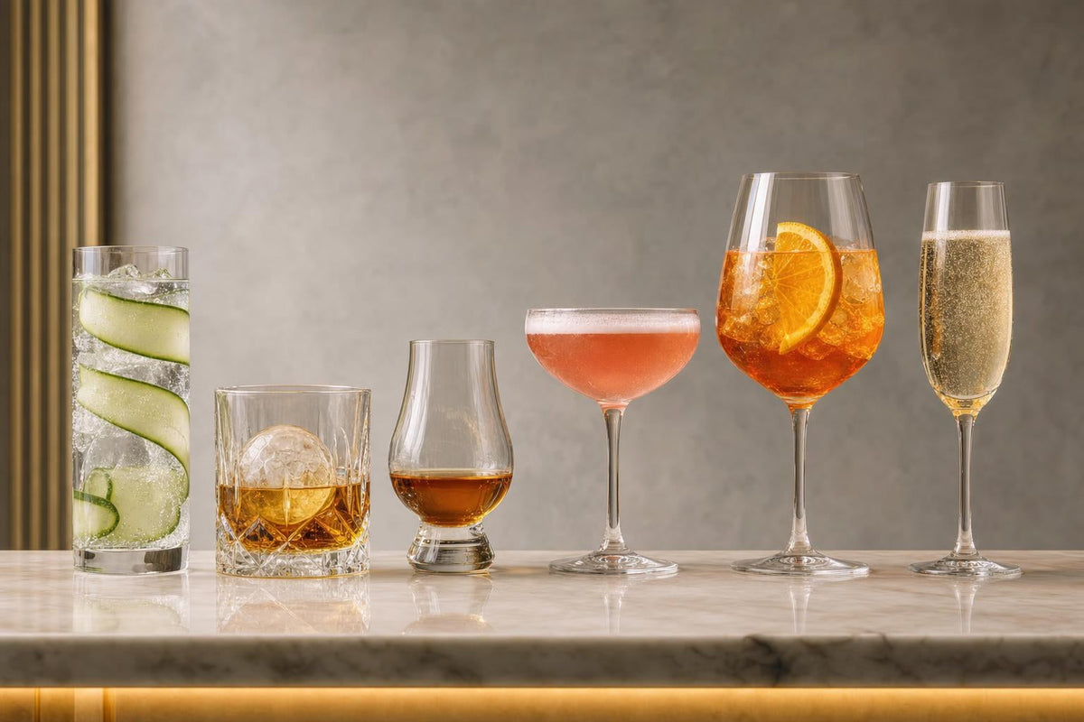 Verschiedene Gläser nebeneinander: Longdrinkglas, Tumbler, Nosing-Glas, Cocktailschale, Weinglas und Sektglas mit passenden Drinks